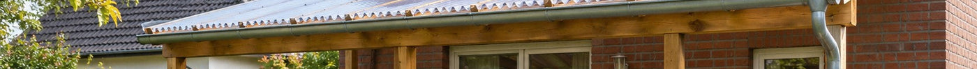 Terrassenüberdachung aus Holz mit klaren Wellplatten an einem Klinkerhaus – Deutsche Kunststoffbedachungen