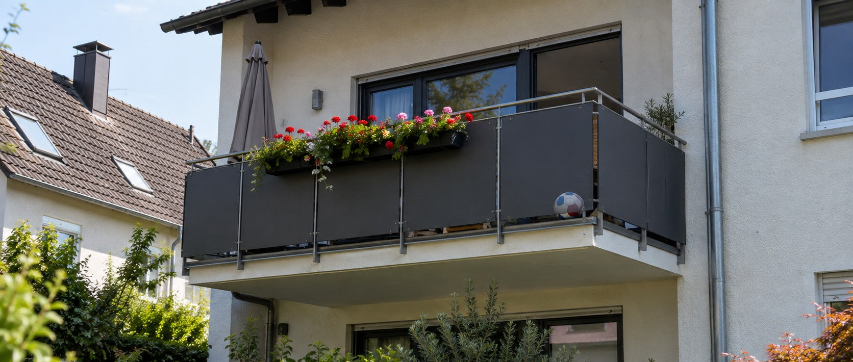 Balkonbrüstung mit robusten HPL-Balkonplatten in Anthrazit und Blumenkasten an einem Wohnhaus – Deutsche Kunststoffbedachungen