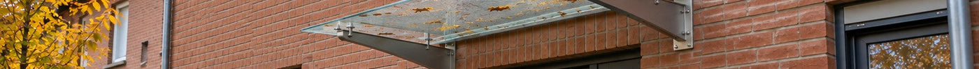 Pultvordach aus Acrylglas mit Edelstahlträgern über der Haustür eines Klinker-Reihenhauses im Herbst – Deutsche Kunststoffbedachungen