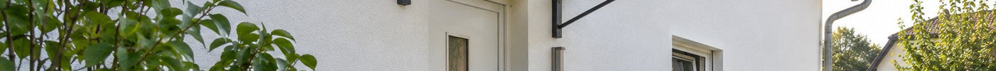 Anthrazitfarbenes Pultvordach über dem Nebeneingang eines Einfamilienhauses mit Stufen und Mülltonnen – Deutsche Kunststoffbedachungen